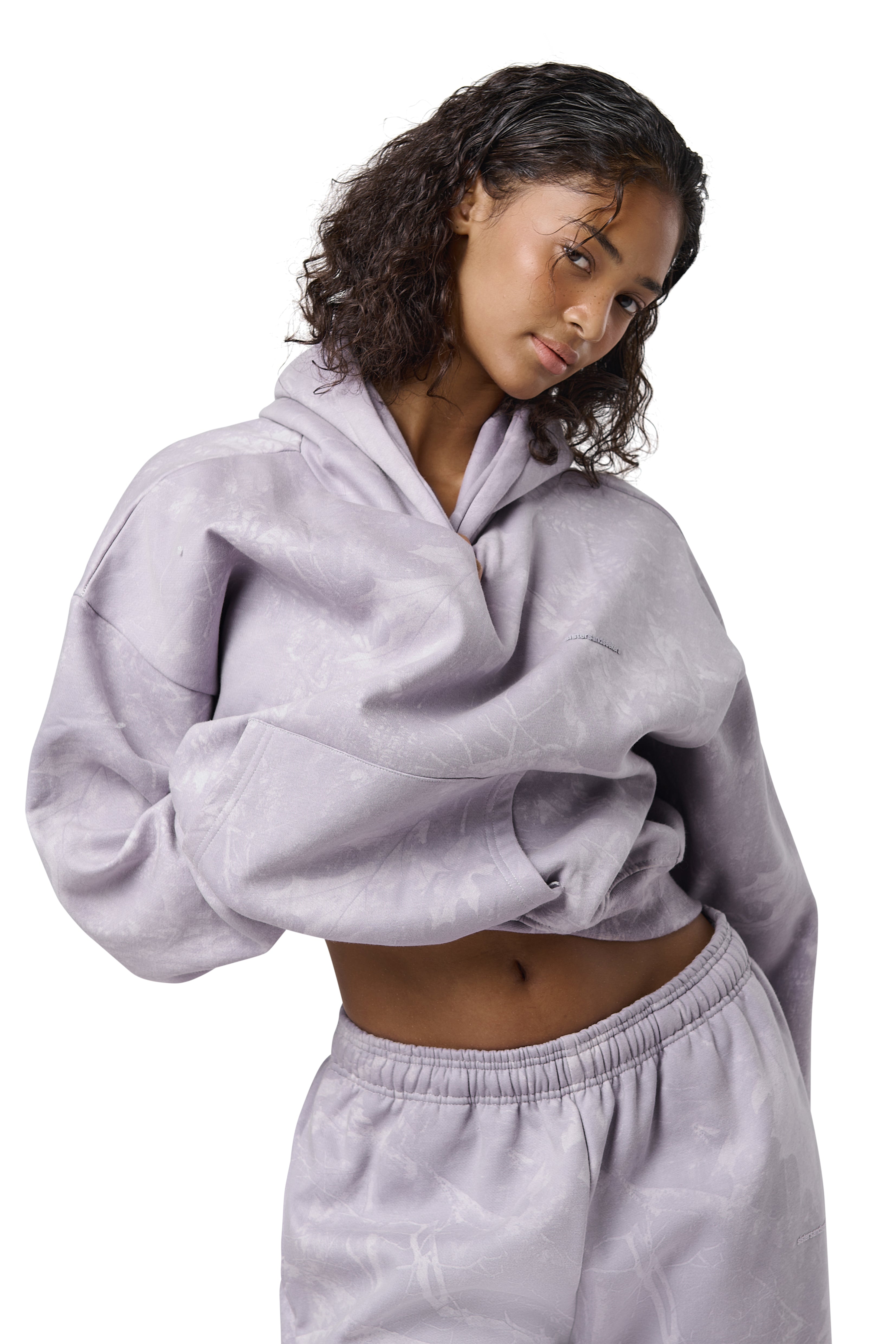 A lilac cropped hoodie with an all-over twig camouflage print, featuring a cropped relaxed fit, dropped shoulders, thick ribbed trims, and embroidered Sisters & Seekers logo.